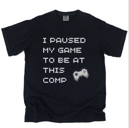 Black t-shirt with text 'I paused my game to be at this comp' and a pixelated game controller on a black background