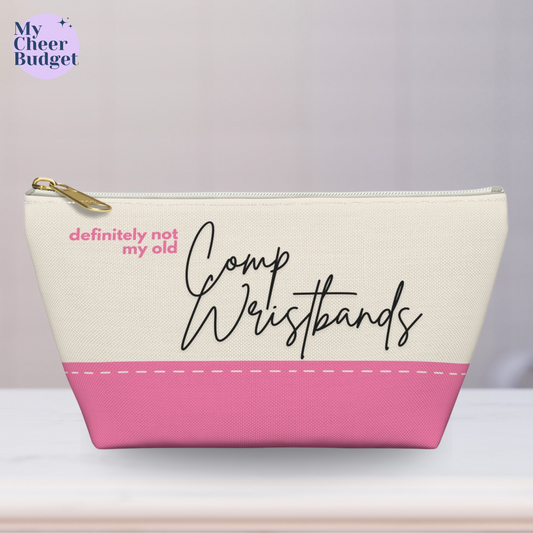 Small zippered pouch bag for cheer moms, cream color printed with "definitely not my old comp wristbands" in pink and black accents