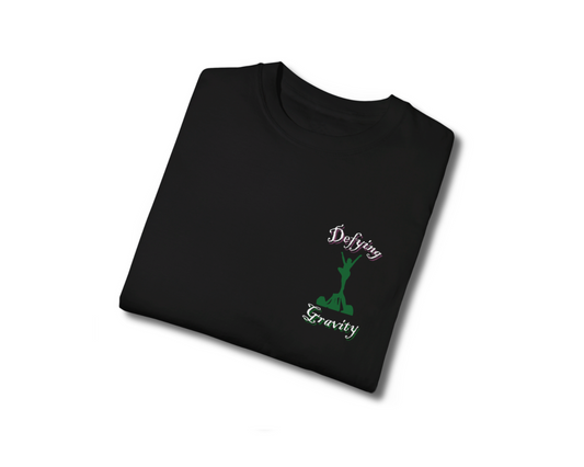 Wicked movie inspired cheer shirt that says defying gravity with graphic of cheer stunt